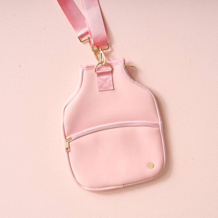 The Darling Effect Blush Pickleball Paddle Case is a pink neoprene crossbody with a slanted zipper pocket and gold hardware, ideal for carrying essentials or your pickleball paddle on the go.