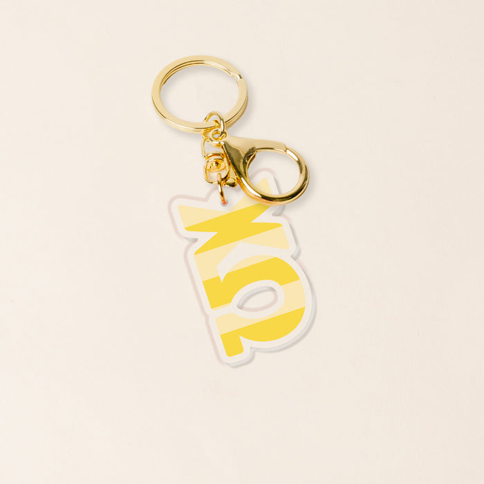 The Darling Effect’s Chi Omega Stripes Acrylic Keychain features gold and yellow accents with bold “15X” on a yellow charm, displayed on an off-white background—an ideal sorority gift or bid day keepsake.