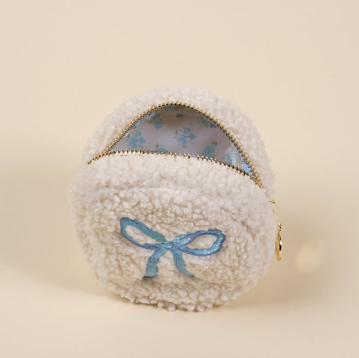 The-darling-effect's Circle Bow Blue Teddy Pouch is a small, round sherpa pouch with a gold zipper, blue embroidered bow, and light blue floral lining—a charming accessory for your collection.