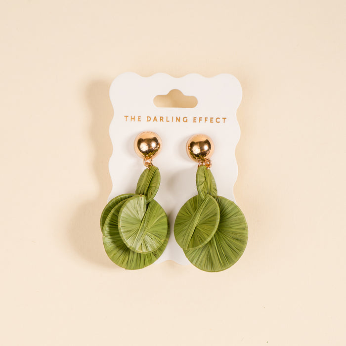 Green Pretty and Polished Earrings by The Darling Effect feature round green leaf-patterned designs with gold studs—ideal for elevating your everyday style. Shown on a white card against a beige background.