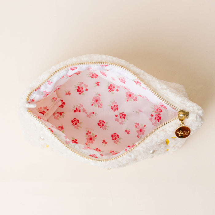 The Darling Effect's Kappa Alpha Theta Bows & Pearls Teddy Pouch is a small white sherpa pouch with embroidered bows, a gold charm zipper, and pink floral lining—perfect as a cute sorority gift.