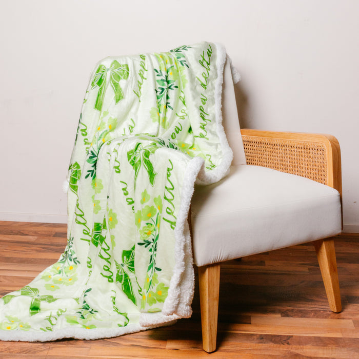 The Kappa Delta Plush Sherpa Blanket by The Darling Effect features a white and green leafy design with “grow a better you” text—perfect as a cozy college dorm throw to drape over any chair or bed.