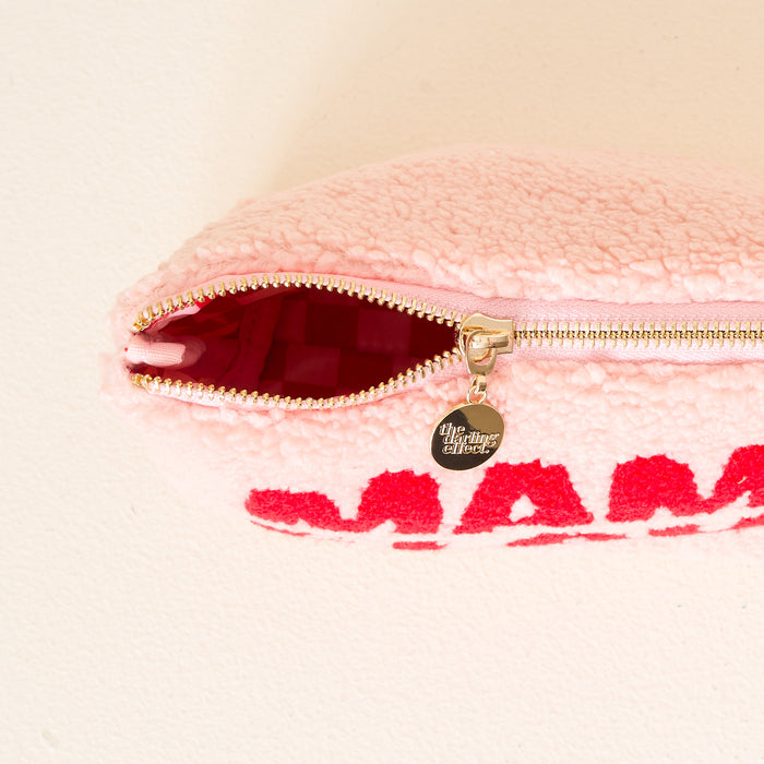The Darling Effect's Mama Claus Teddy Pouch features soft pink fuzzy fabric, bold red "Mama Claus" lettering, gold zipper hardware with a round charm, and a red-lined interior—an ideal travel accessory from the Christmas Teddy Pouches collection.