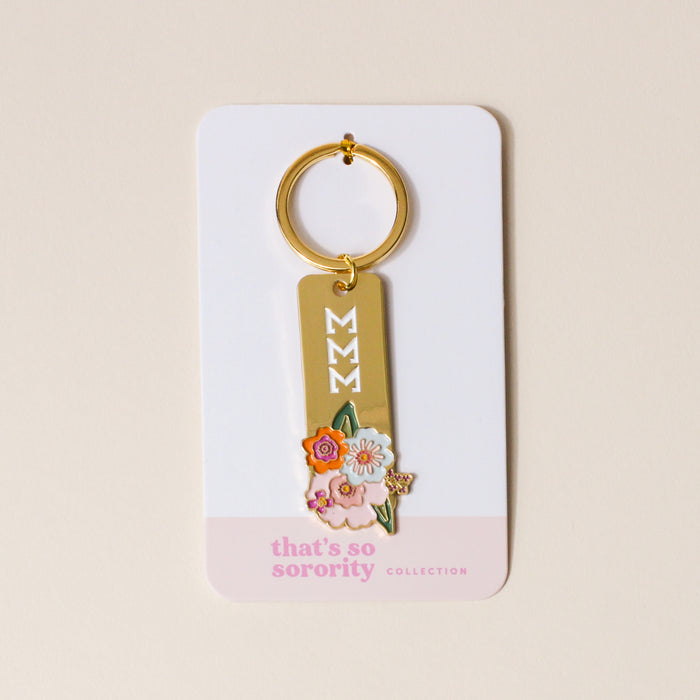 The Darling Effect’s Sigma Sigma Sigma Enamel Keychain features three white Ms with colorful florals on a white card marked "thats so sorority COLLECTION"—a perfect sorority gift.