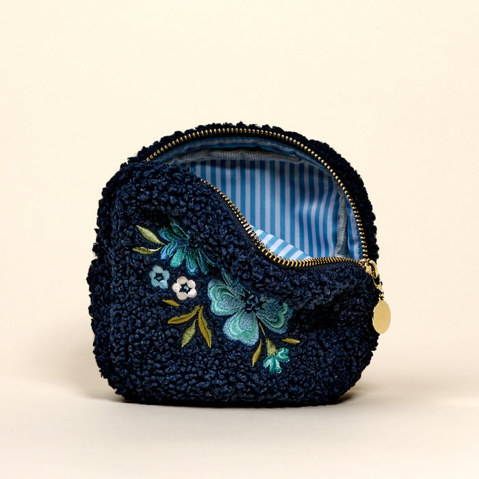 The Square Dainty Floral Navy Teddy Pouch by the-darling-effect is a small, textured navy pouch with floral embroidery, a gold zipper, and blue-and-white striped lining.