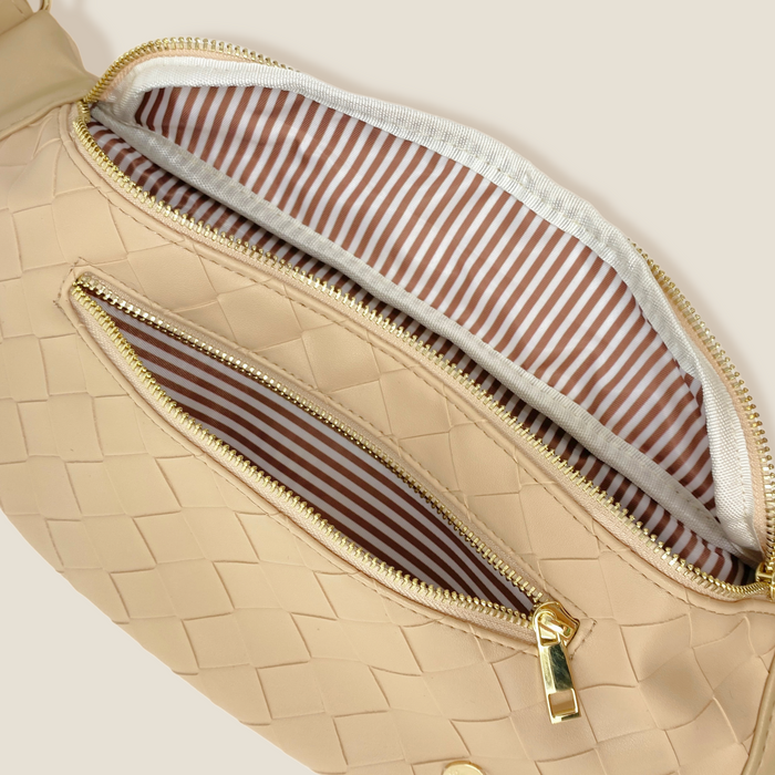 The Darling Effect's Woven Oat Trendy Luxe Belt Bag features beige woven fabric, gold zippers, a brown and white striped lining, a spacious main compartment, and a front pocket—ideal for adding style to any outfit.