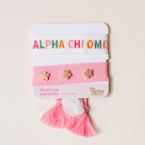 The Darling Effect Alpha Chi Omega Woven Bracelet Set features a white bracelet with ALPHA CHI OMEGA in colorful letters and a pink band with gold flower studs, pink/white tassels—an ideal sorority gift.