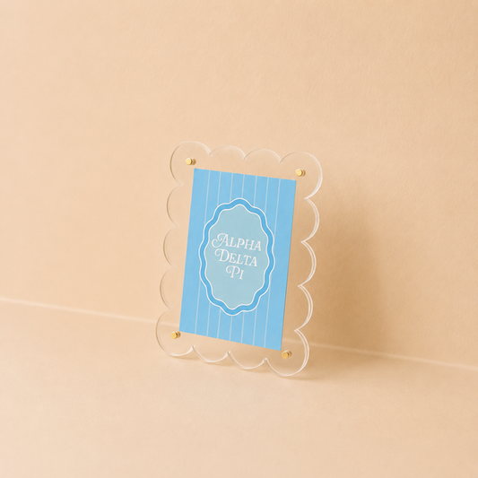 The Darling Effect's Alpha Delta Pi Mini Acrylic Picture Frame Magnet features a scalloped clear border and holds a blue card with "Alpha Delta Pi" in white script—perfect for decorating your mini fridge.