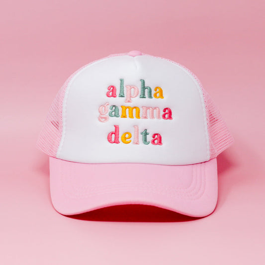 The Darling Effect’s Alpha Gamma Delta Pink Trucker Hat features a white front panel embroidered with colorful, lowercase letters—perfect for gifting or as a cute sorority accessory.