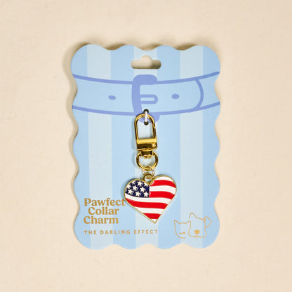 The Darling Effect Americana Heart Pawfect Collar Charm features a heart-shaped American flag design, gold clasp, and blue packaging with two pet illustrations—a patriotic accessory for your pet.