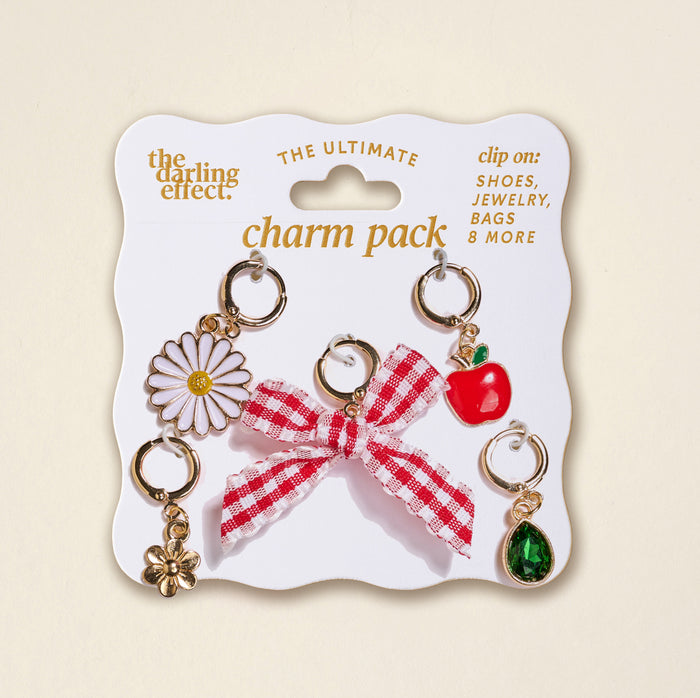 The Darling Effect’s Apple of My Eye The Ultimate Charm Pack includes daisy, flower, red gingham bow, apple, and green gem charms on a white card—perfect to pair with Scrunchie Charm Sets or Make a Statement Necklaces.