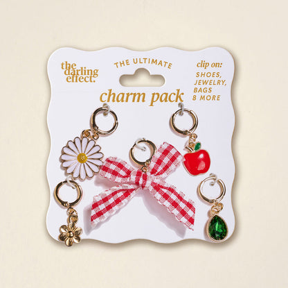 The Darling Effect’s Apple of My Eye The Ultimate Charm Pack includes daisy, flower, red gingham bow, apple, and green gem charms on a white card—perfect to pair with Scrunchie Charm Sets or Make a Statement Necklaces.