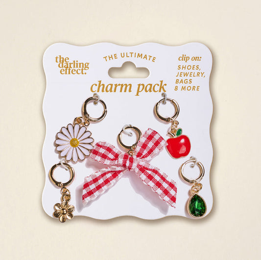 The Darling Effect’s Apple of My Eye The Ultimate Charm Pack includes daisy, flower, red gingham bow, apple, and green gem charms on a white card—perfect to pair with Scrunchie Charm Sets or Make a Statement Necklaces.