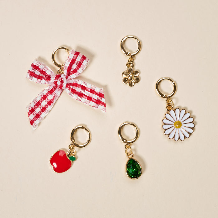 This set of four gold earrings features a red and white gingham bow, gold flower, white daisy with yellow center, and red apple—perfect for mixing and matching with The Darling Effect Apple of My Eye The Ultimate Charm Pack.