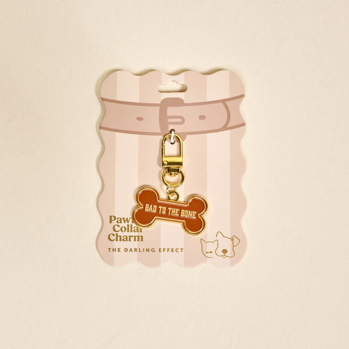 The Darling Effect's Bad to the Bone Pawfect Collar Charm features a bone-shaped design and gold clasp, displayed on packaging with cute collar and dog illustrations—a playful addition to your pet's accessories.