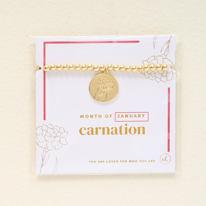 The Darling Effect Birth Flower Beaded Charm Bracelet features a gold beaded design with a round carnation-engraved charm for January, displayed on a card that says “You are loved for who you are”—a meaningful, personalized jewelry piece.
