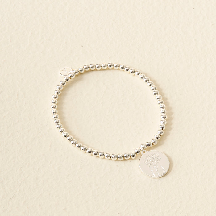 The Darling Effect Birth Flower Beaded Charm Bracelet features a silver beaded design with a circular charm engraved with a delicate floral motif—ideal as personalized jewelry or a meaningful birth flower bracelet.