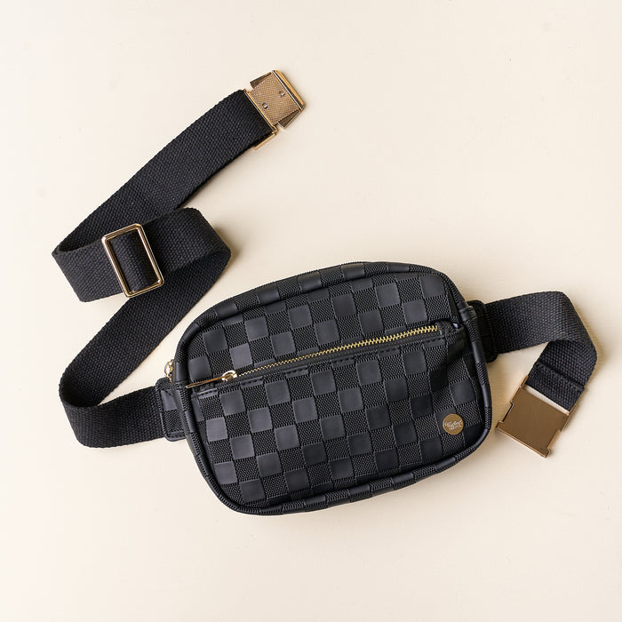 The Darling Effect’s Black Urban Check Belt Bag, crafted from vegan leather with a gold zipper and buckle, has an adjustable strap with sleek metal hardware and is displayed flat on a light beige background.