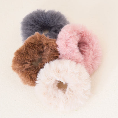 The Bliss Faux Fur Scrunchie Set by The Darling Effect features four fluffy scrunchies in grey, brown, pink, and cream—perfect luxury hair accessories for any style.