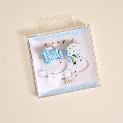 The Darling Effect's Blooming Bride Straw Topper Set includes two leak-resistant silicone toppers: a blue "Bride" with diamond and a white flower bouquet, both displayed on a chic blue and white striped background.