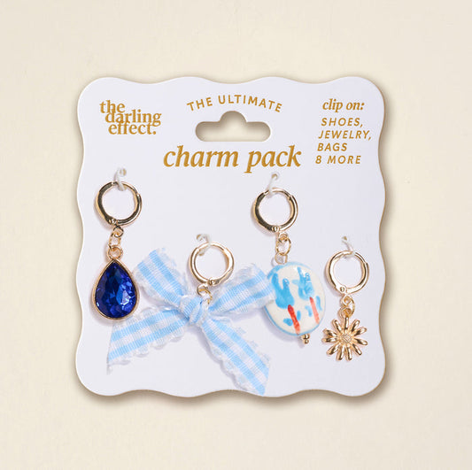 Blue Belle The Ultimate Charm Pack by The Darling Effect features four gold charms—a blue teardrop gem, a blue gingham ribbon bow, a painted bead, and a gold sunburst—perfect for customizing your statement necklaces.