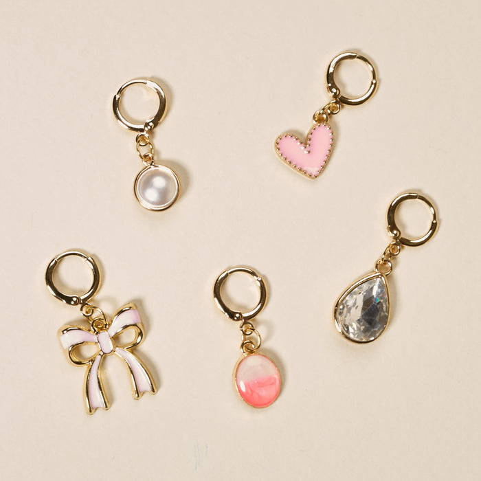 The Darling Effect’s Blush Crush The Ultimate Charm Pack features five gold keychain charms—a white pearl, pink heart, clear teardrop gem, pink and white bow, and a pink oval gem—perfect for scrunchie sets or statement necklaces.