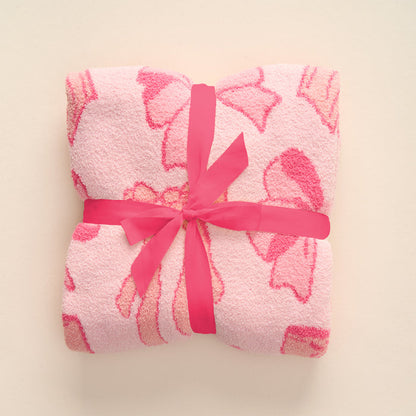 The-darling-effect Blushing Bows Pink Cozy Dreams Luxe Blanket, crafted from ultra-soft polyester microfiber with a hot pink floral pattern and satin ribbon, is shown folded on a cream background.
