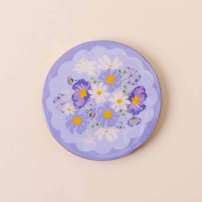 The-darling-effect’s Bouquet Beauty Purple Wood Enamel Coaster features white daisies, yellow centers, and purple pansies on a periwinkle background with scalloped edges—a stylish and durable decorative piece.