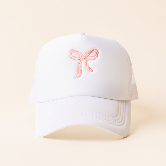 The Bow Pink Trucker Hat by the-darling-effect is a trendy white hat with a pink embroidered bow—perfect for stylish embroidered hat lovers.