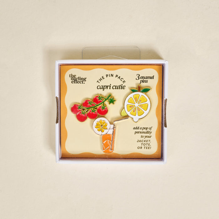 Capri Cutie The Pin Pack by The Darling Effect features three expressive pins—a lemon slice, tomato vine, and orange drink—to add personality to your jacket, tote, or tee.