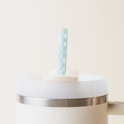 A Check Blue 40 oz Tumbler Straw Set by The Darling Effect features a light blue and white checkered reusable straw in a white tumbler with a metal band, set against a plain beige background.