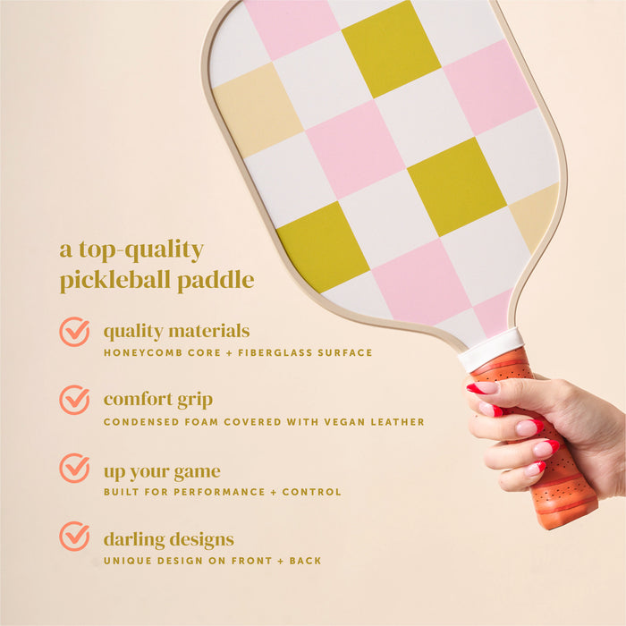 A hand holds The Darling Effect's Check Green Pickleball Paddle, known for its quality materials, comfort grip, standout performance, and unique double-sided green check design.