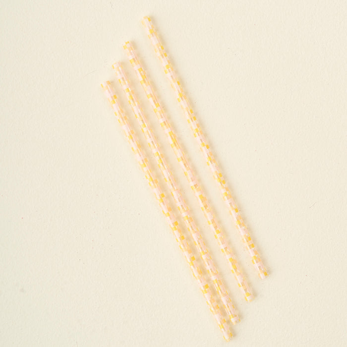 The Darling Effect’s Check Peach 40 oz Tumbler Straw Set features four clear, reusable eco-friendly straws with a yellow and white checkered pattern, arranged diagonally on a plain, light-colored surface.