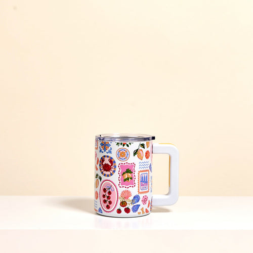 The Darling Effect’s Ciao Bella 14 oz Insulated Mug features a large handle and playful fruit, flower, and abstract designs. Its double-wall insulation keeps drinks hot or cold in style. Shown on a white surface with a beige background.