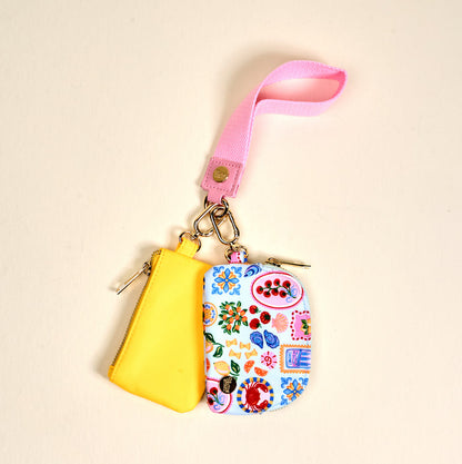 The Darling Effect's Ciao Bella Dynamic Duo Pouch Wristlet pairs a bright yellow pouch and a white Mediterranean-inspired pouch on a pink strap for easy, stylish versatility.