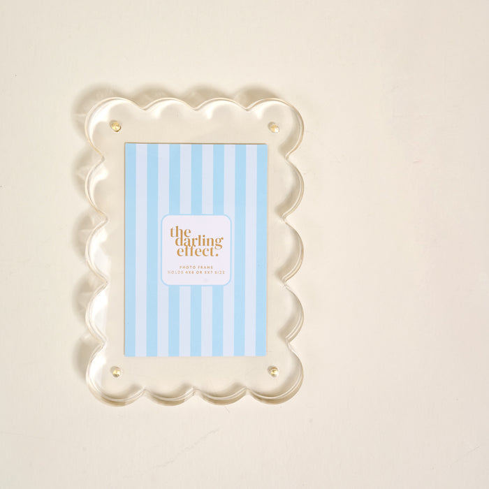 The Clear Rectangle Scalloped Acrylic Frame by the-darling-effect features scalloped edges, gold pins, and a modern design to add a chic touch to your display.