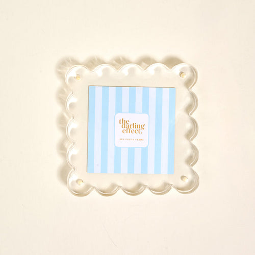 The Clear Square Scalloped Acrylic Frame by the-darling-effect features a blue and white striped insert with “the darling effect,” offering a modern, elegant display from the Scalloped Acrylic Picture Frames collection.