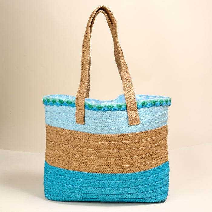 The Darling Effect’s Coastal Breeze Straw & Sun Tote is a lightweight bag with two handles and turquoise, tan, and light blue stripes—ideal for vacation days against any neutral backdrop.