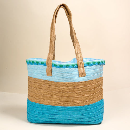The Darling Effect’s Coastal Breeze Straw & Sun Tote is a lightweight bag with two handles and turquoise, tan, and light blue stripes—ideal for vacation days against any neutral backdrop.