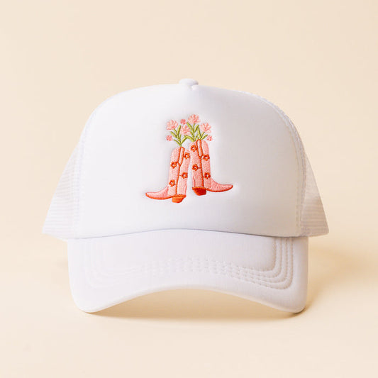 The Cowgirl Boots Trucker Hat by the-darling-effect features a trendy white mesh design with embroidered pink cowboy boots and flowers on the front, perfect for fans of unique and stylish headwear.