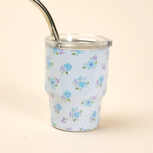 The Dainty Floral Blue 2 oz Tiny Tumbler by the-darling-effect features a light blue design with blue and purple flowers, a clear lid, and a metal straw, photographed on a plain beige background.