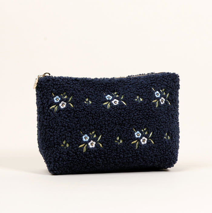 The Dainty Floral Navy Teddy Pouch by the-darling-effect features textured sherpa fabric, small embroidered light blue flowers, and a zipper, shown against a plain light background.