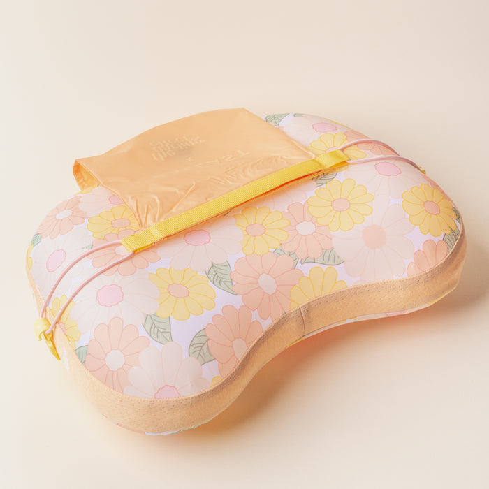 The Darling Effect Daisy Craze Peach Ballast Beach Pillow is a limited-edition pastel floral pillow in yellow, orange, and pink, featuring a yellow strap and attached peach pouch, shown on a light beige background.
