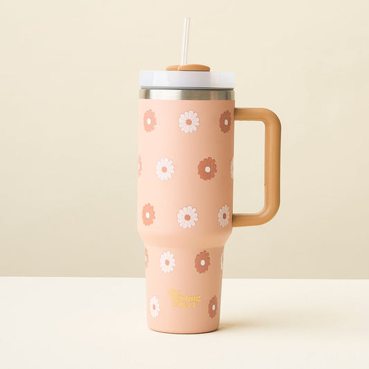The Darling Effect Darling Daisy Tan 40 oz Take Me Everywhere Tumbler features a large handle, clear lid, straw, and peach daisy-like flower design. It sits on a light surface against a beige background.