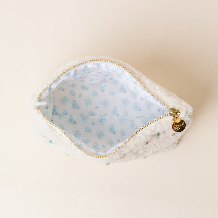 The Darling Effect's Delta Delta Delta Bows & Pearls Teddy Pouch features fluffy white sherpa, blue floral lining, bow embroidery, and a gold zipper charm—making it a perfect sorority gift.