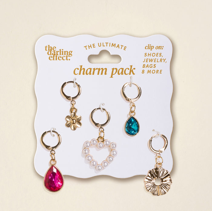 The Darling Effect’s Enchanted The Ultimate Charm Pack includes five clip-on charms—a gold flower, teal teardrop, pearl heart, pink teardrop, and gold sunburst—perfect for customizing statement necklaces.