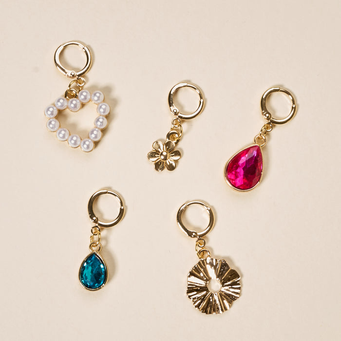 The Darling Effect’s Enchanted The Ultimate Charm Pack features five gold charms—a heart with pearls, a small flower, pink and blue teardrops, and a sunburst—ideal for collectors or pairing with scrunchie charm sets.