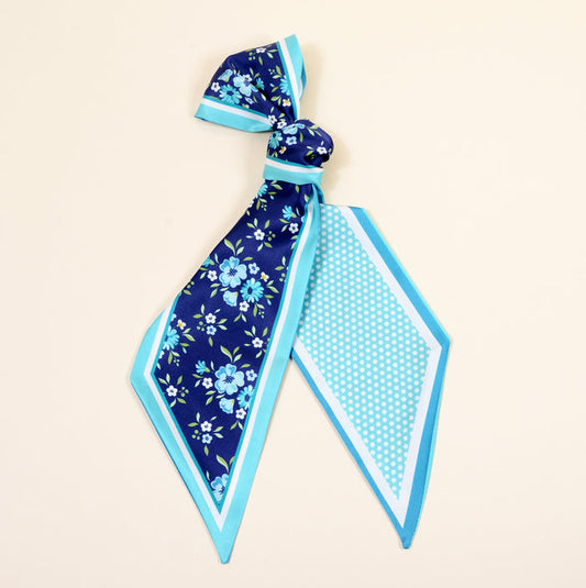The Darling Effect's Endless Daydream Navy Twirl & Tie Scarf Accessory features a knotted top, blue floral print on one side, blue and white polka dots on the other, and light blue/turquoise borders—perfect for endless styling options.