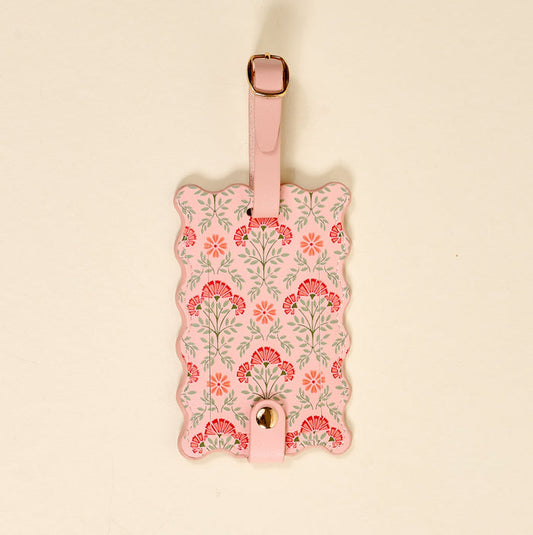 The Darling Effect’s Everbloom Dusty Rose Jetsetter Luggage Tag features a pink block-print floral design with green leaves, scalloped edges, privacy flap, pink leather strap, gold-tone buckle, and snap closure—a stylish travel accessory.