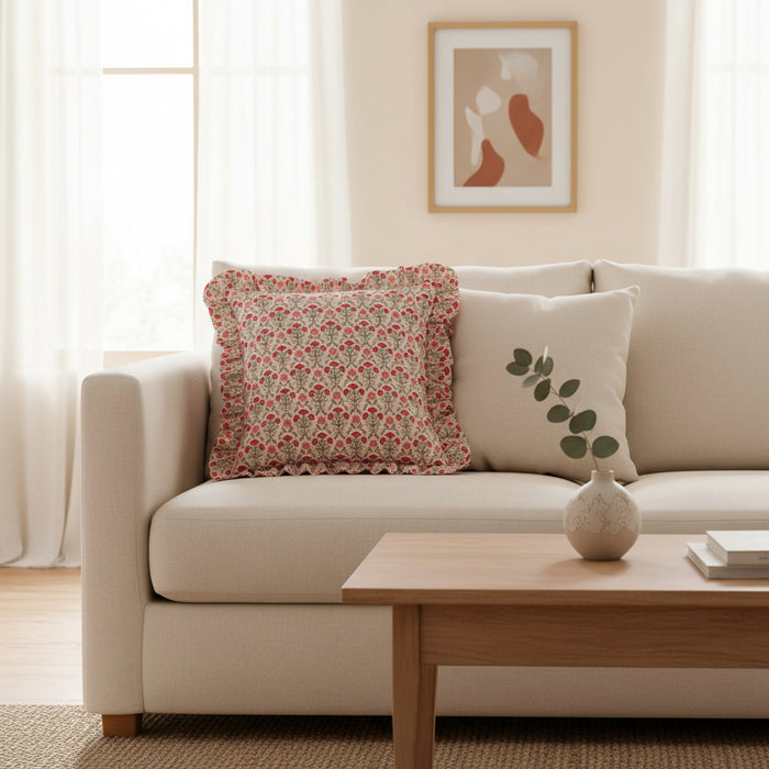 A cream sofa with The Darling Effect Everbloom Dusty Rose Scalloped Square Throw Pillow and a vase with eucalyptus on a wooden coffee table.